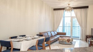 A modern living room with a dining area, a leather sofa, and a chandelier.