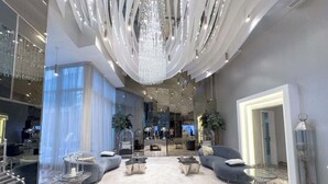 Eine geräumige Lobby mit Marmorboden, moderner Sitzgelegenheit und einem großen Chandelier.