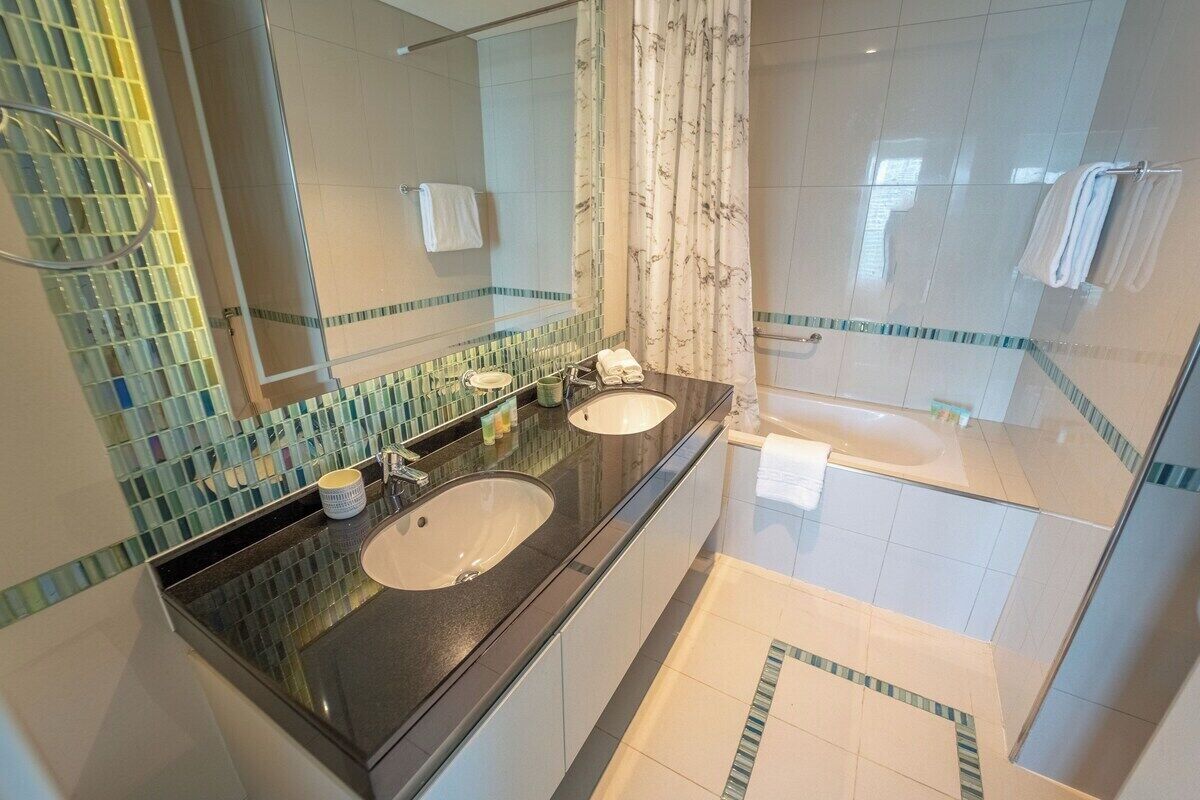 Une salle de bain moderne avec deux lavabos, un grand miroir et un espace douche.