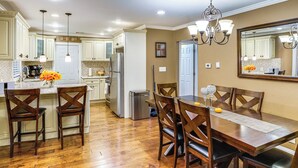 A kitchen with wooden flooring, white cabinets, a dining table with chairs, and a chandelier. - Private Hot Tub on 10 Acres: Cozy Catskill Getaway (Catskill)