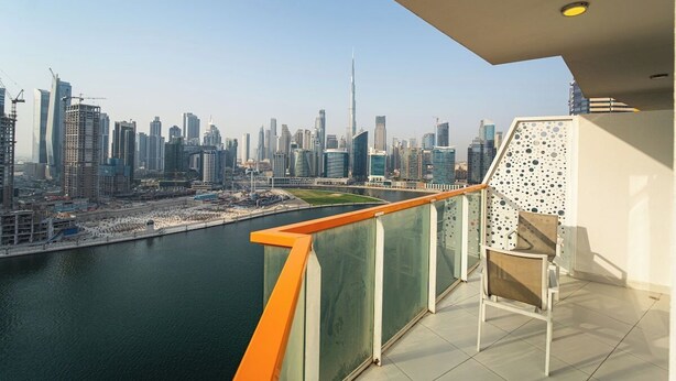 Un balcón con vista a un horizonte urbano, incluyendo una torre destacada.