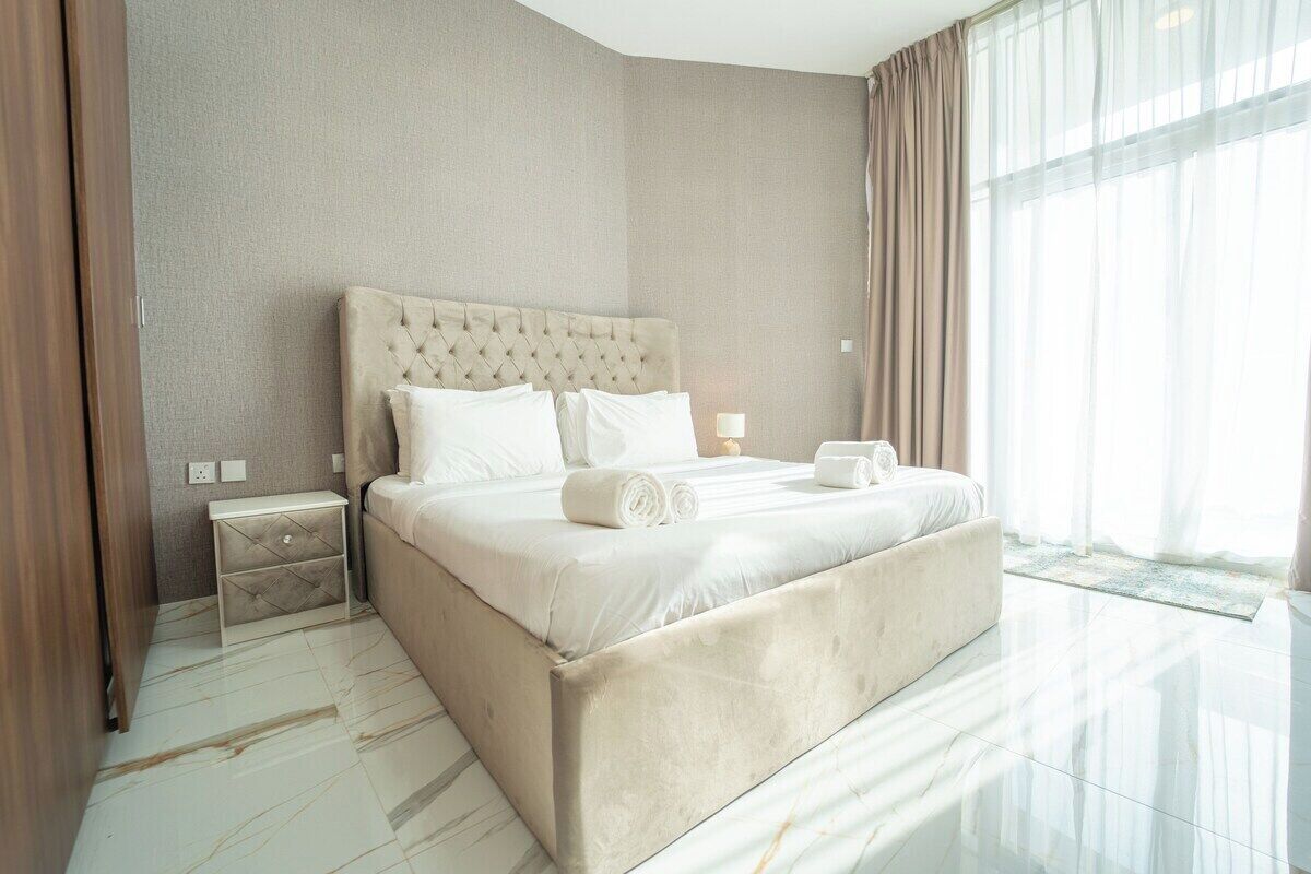 Quarto de hotel moderno com uma cama grande, mesa de cabeceira e vista para o exterior.