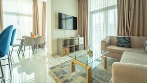 Una sala moderna con sofá, mesa de centro y televisor. Hay un comedor con sillas y una mesa.