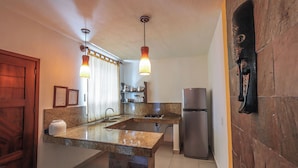 A kitchen with granite countertops, a stainless steel refrigerator, and pendant lighting. - Hotel & Villas Quinta Minas (Los Ayala)