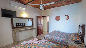 A hotel room with two beds, a TV, an air conditioner, a ceiling fan, and a door leading to another room. - Hotel & Villas Quinta Minas (Los Ayala)
