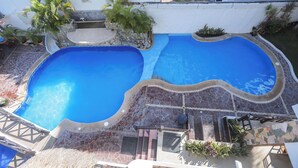 A swimming pool with a stone deck, surrounded by potted plants and a small seating area. - Hotel & Villas Quinta Minas (Los Ayala)