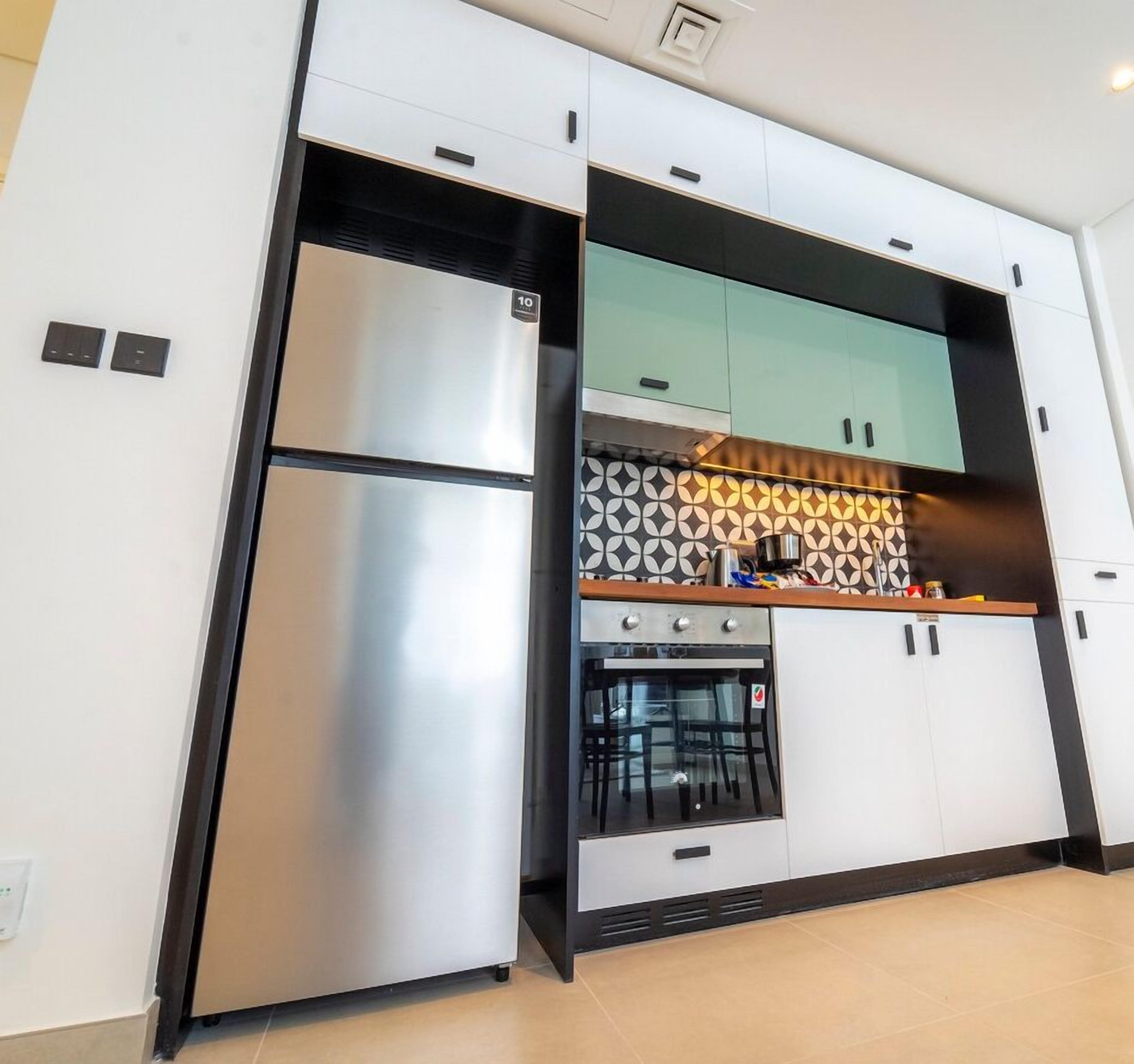 A modern kitchen with stainless steel appliances, a built-in oven, and a patterned backsplash.