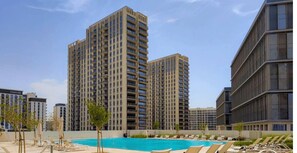 A high-rise residential building with a swimming pool and lounge chairs.