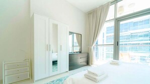 Ein Hotelzimmer mit Bett, Schrank, Spiegel und Fenster mit Blick auf Gebäude.