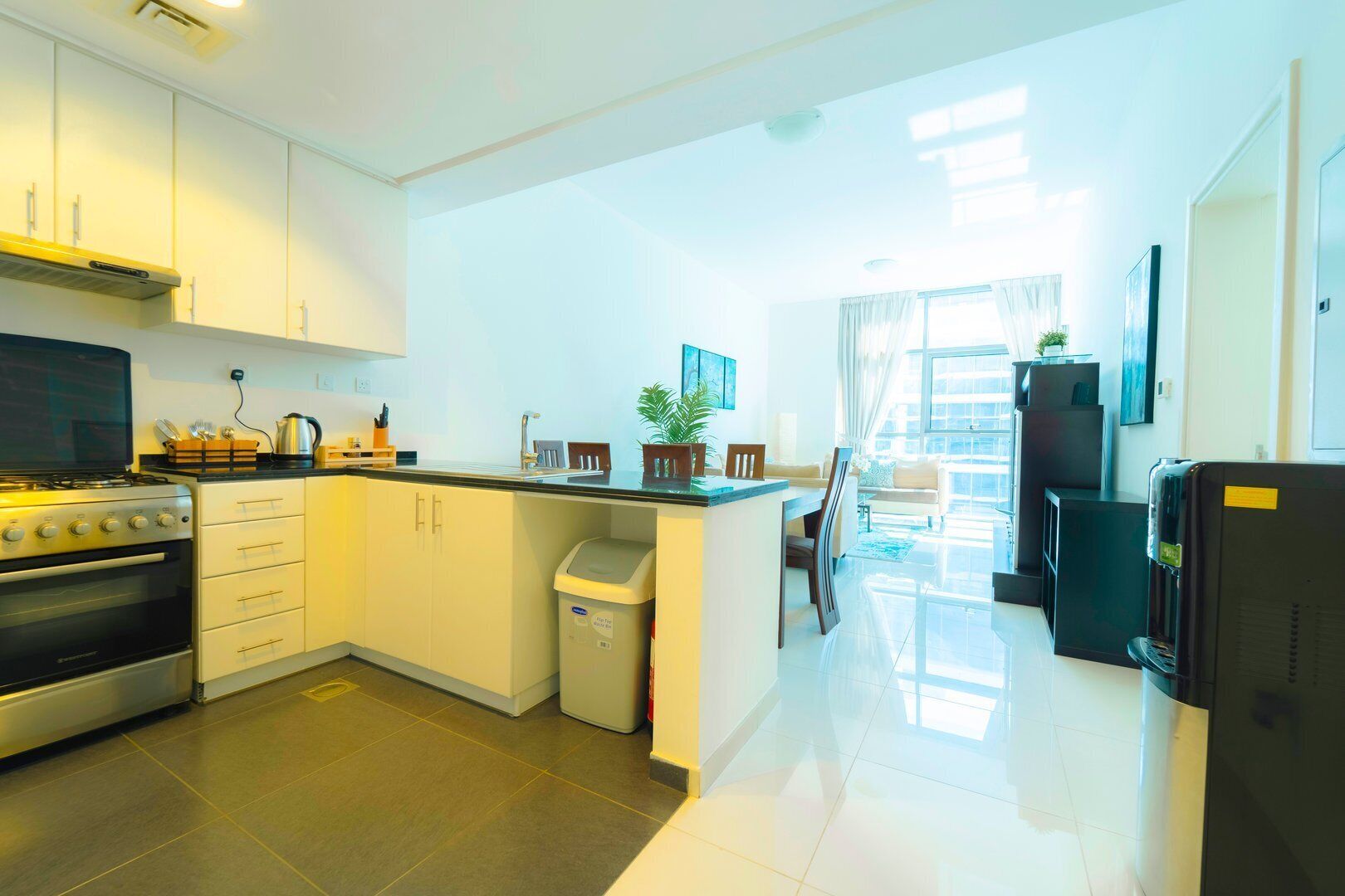 Une cuisine moderne avec des meubles blancs, une cuisinière et un coin repas comprenant une table et des chaises.