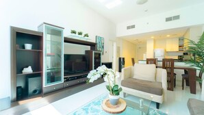 Ein modernes Wohnzimmer mit Flachbildfernseher, einem Glastisch und einer weißen Orchideenpflanze.