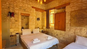 Un dormitorio de paredes de piedra con dos camas, techo de madera y una lámpara colgante.