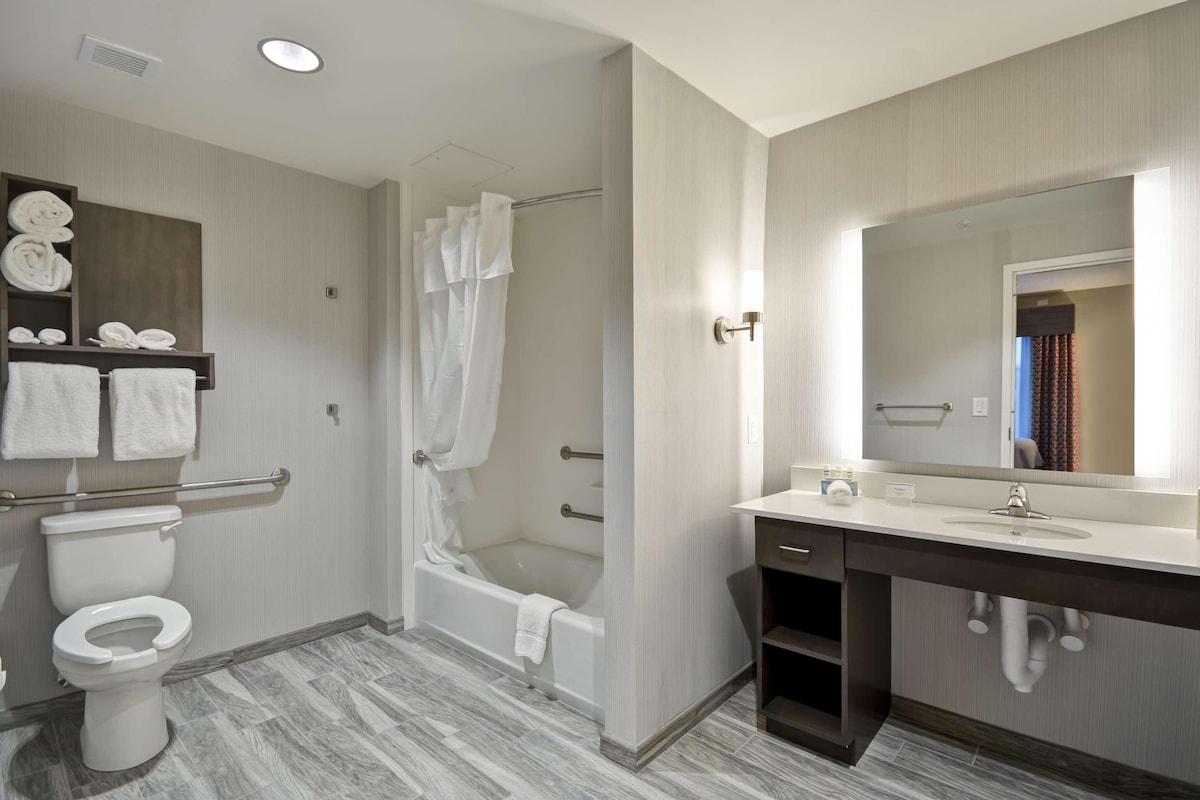 Un baño moderno con inodoro, ducha, bañera y tocador con espejo.