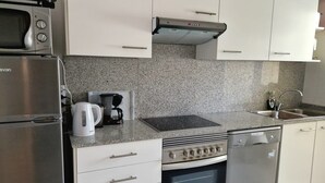 A modern kitchen with a built-in microwave, coffee maker, stove, oven, and dishwasher. - Charming 2-bedroom apartment with WiFi, AC in fantastic Platja de l'Arenal (Platja de l'Arenal)