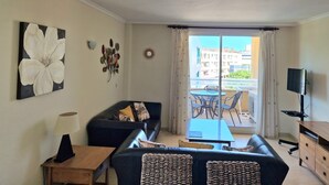 A living room with a sofa, a coffee table, a TV, and a balcony with outdoor furniture. - Charming 2-bedroom apartment with WiFi, AC in fantastic Platja de l'Arenal (Platja de l'Arenal)