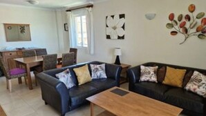 A living room with two sofas, a coffee table, and a dining area with chairs and a table. - Charming 2-bedroom apartment with WiFi, AC in fantastic Platja de l'Arenal (Platja de l'Arenal)