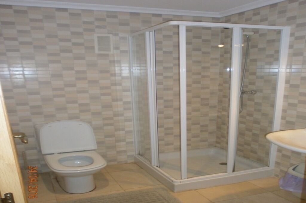 Une salle de bain comprenant des toilettes, une douche à parois de verre et un lavabo.