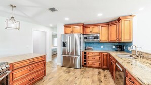 A modern kitchen with wooden cabinets, stainless steel appliances, and granite countertops. - Enchanting, this four-bedroom, three-bath home promises stunning sunset views every evening. (Marco Island)