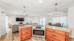 A modern kitchen with a central island, stainless steel appliances, and wooden cabinetry. - Enchanting, this four-bedroom, three-bath home promises stunning sunset views every evening. (Marco Island)
