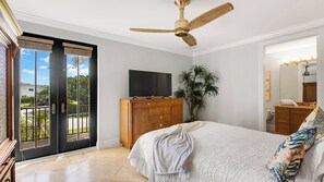 Une chambre à coucher comprenant un lit, une commode en bois, un téléviseur et un ventilateur de plafond.