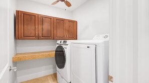 Une buanderie équipée d’un lave-linge, d’un sèche-linge, de meubles en bois et d’un plan de travail.