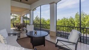 A balcony with a round table and chairs, a sofa, and a view of trees and sky. - Coastal Paradise Awaits: Luxurious Beachside House with Top-Notch Amenities (Marco Island)