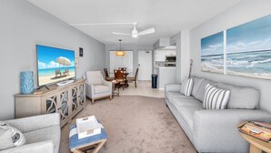 Un salon comprenant un téléviseur, un canapé, une table basse et un coin repas avec des chaises et une table.