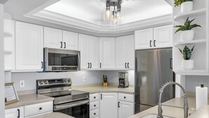 Une cuisine moderne avec des meubles blancs, des appareils en acier inoxydable et un four encastré.