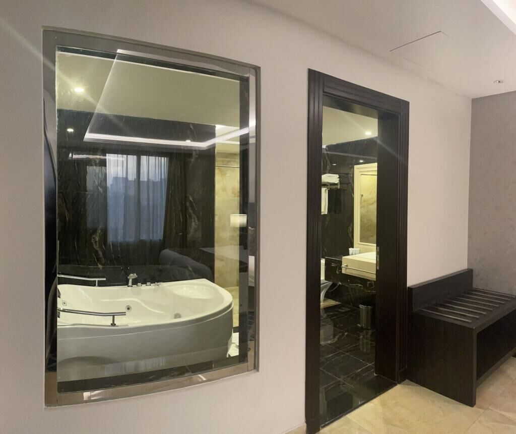 A modern bathroom with a large mirror, a bathtub, and a vanity.