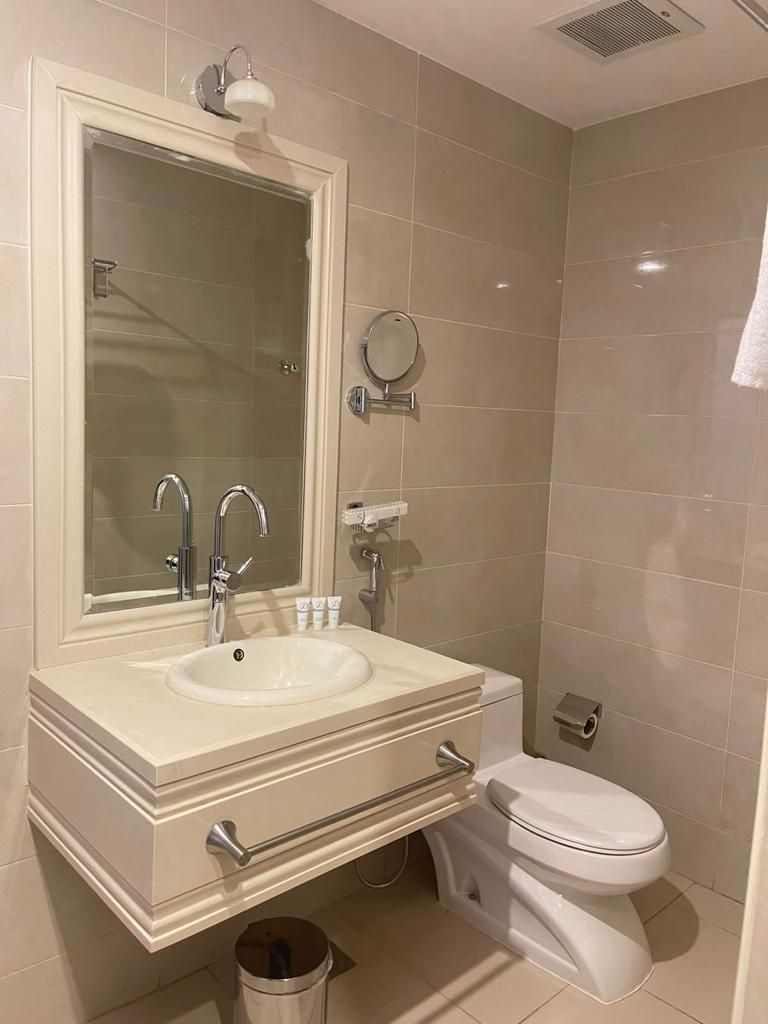 A bathroom with a double sink, a toilet, and a mirror.