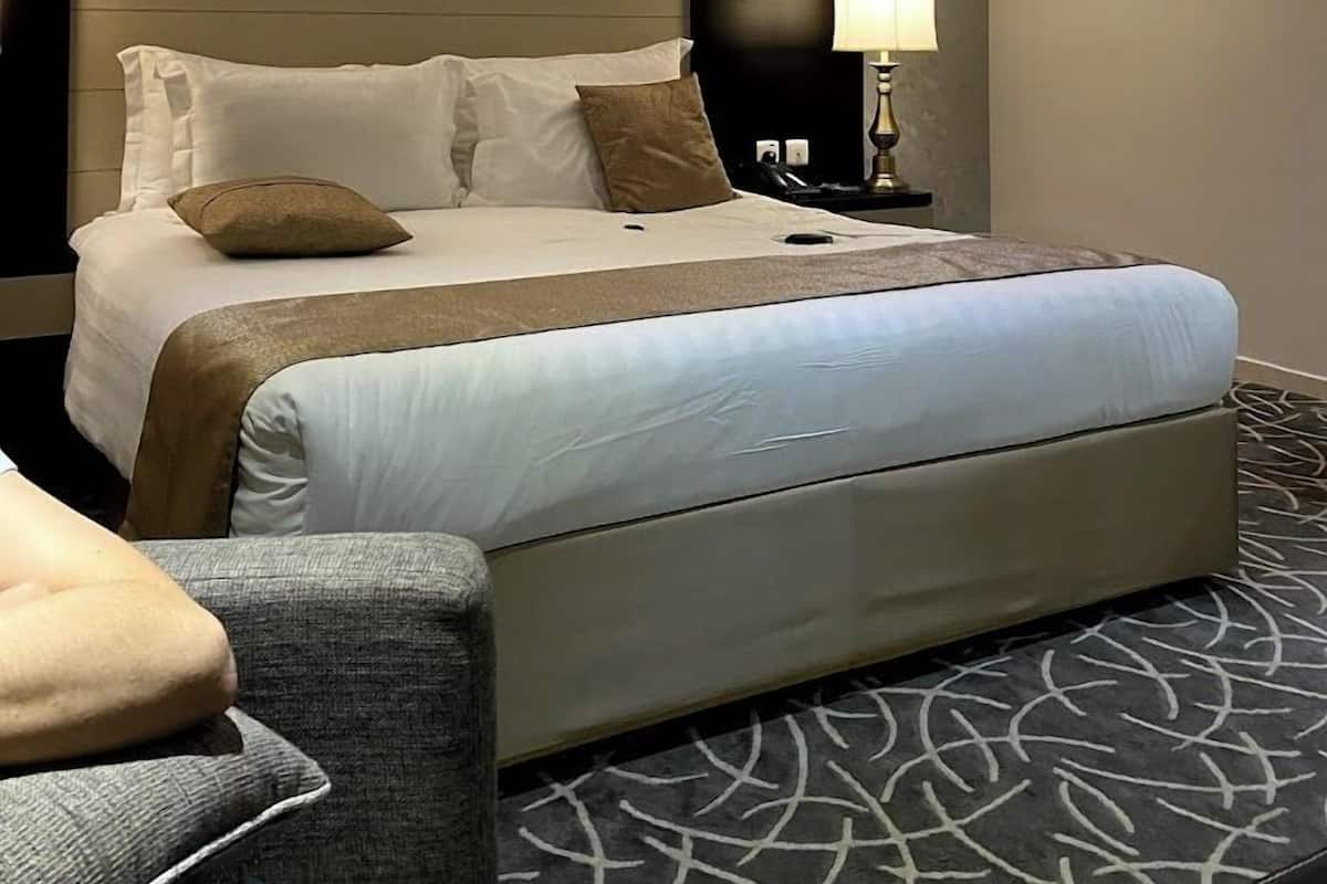 A hotel room with a large bed, a bedside table with a lamp, and a chair.