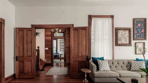 A living room with a sofa, a coffee table, and a wooden door leading to another room.