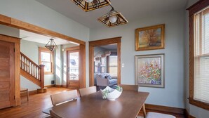 A dining area with a wooden table, chairs, and a bench. There is a staircase with wooden railings leading to another room. - Robin's Egg ~ Private Downtown, Pet-Friendly Gem (Columbus)