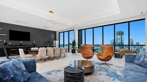 A modern living room with a large TV, comfortable seating, and a city view.