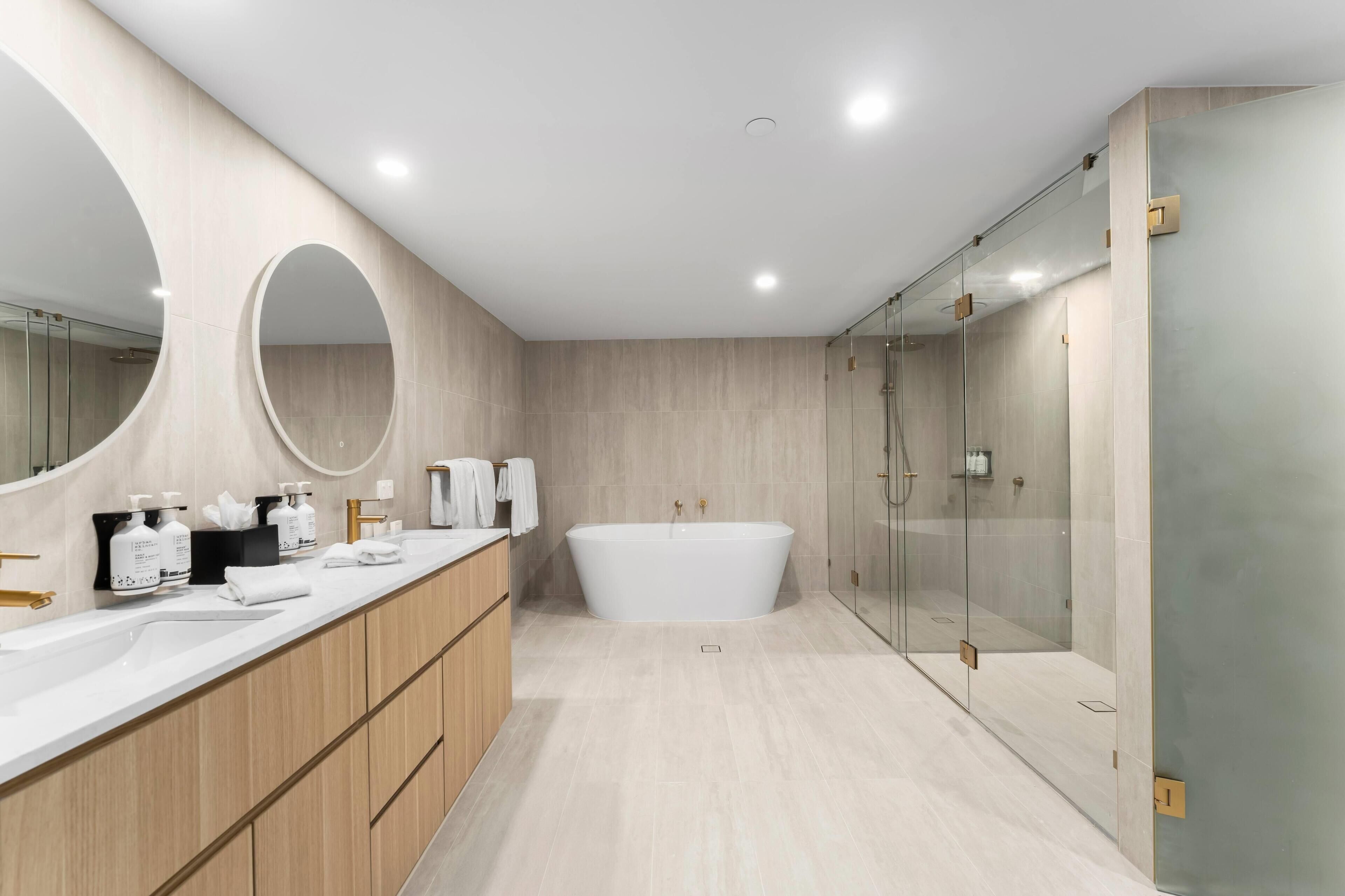 Un baño moderno con una bañera independiente, un espejo grande y una ducha con mampara de vidrio.