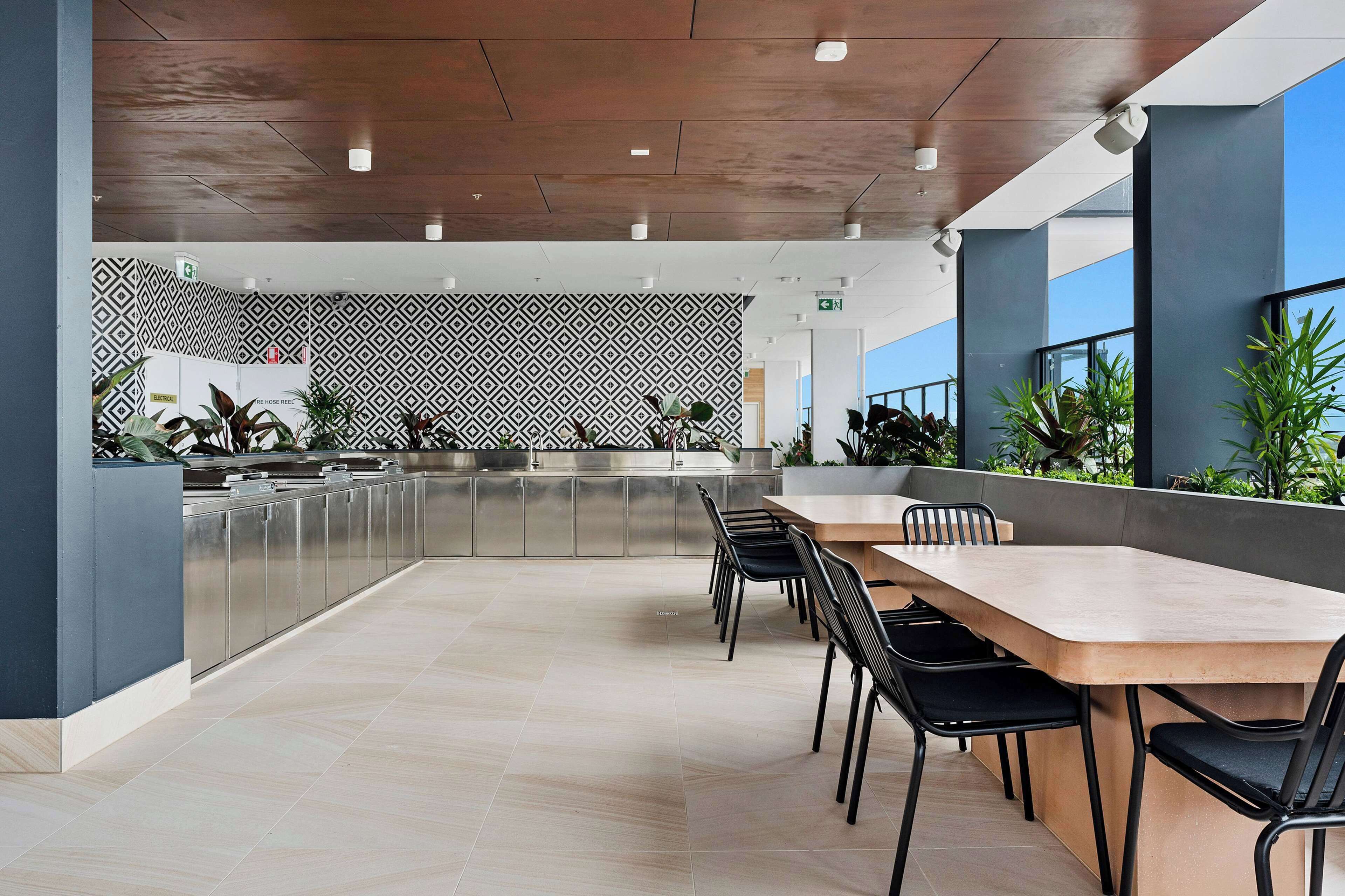 A modern kitchen with stainless steel appliances, a patterned wall, and a dining area with a long table and chairs.