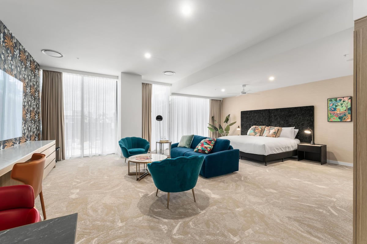 Une chambre d’hôtel moderne équipée d’un lit, d’un bureau, d’une chaise, d’un canapé et d’une petite table.