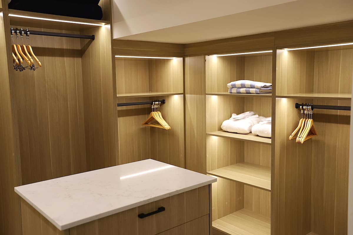 Un placard moderne avec des portes en bois, un comptoir en marbre et des étagères pour suspendre les vêtements.