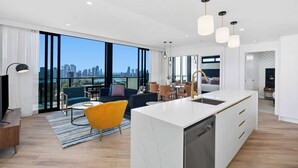 A modern apartment with a large kitchen island, dining area, and a living space with a city view.