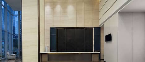 A modern lobby with a marble floor, a seating area, and a large window.