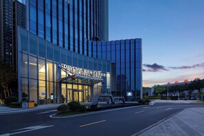 Un moderno edificio de hotel con fachada de vidrio y señalización en varios idiomas.