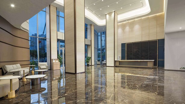 A spacious lobby with high ceilings, large windows, and a polished marble floor.