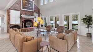A spacious living room with a fireplace, comfortable seating, and large windows.