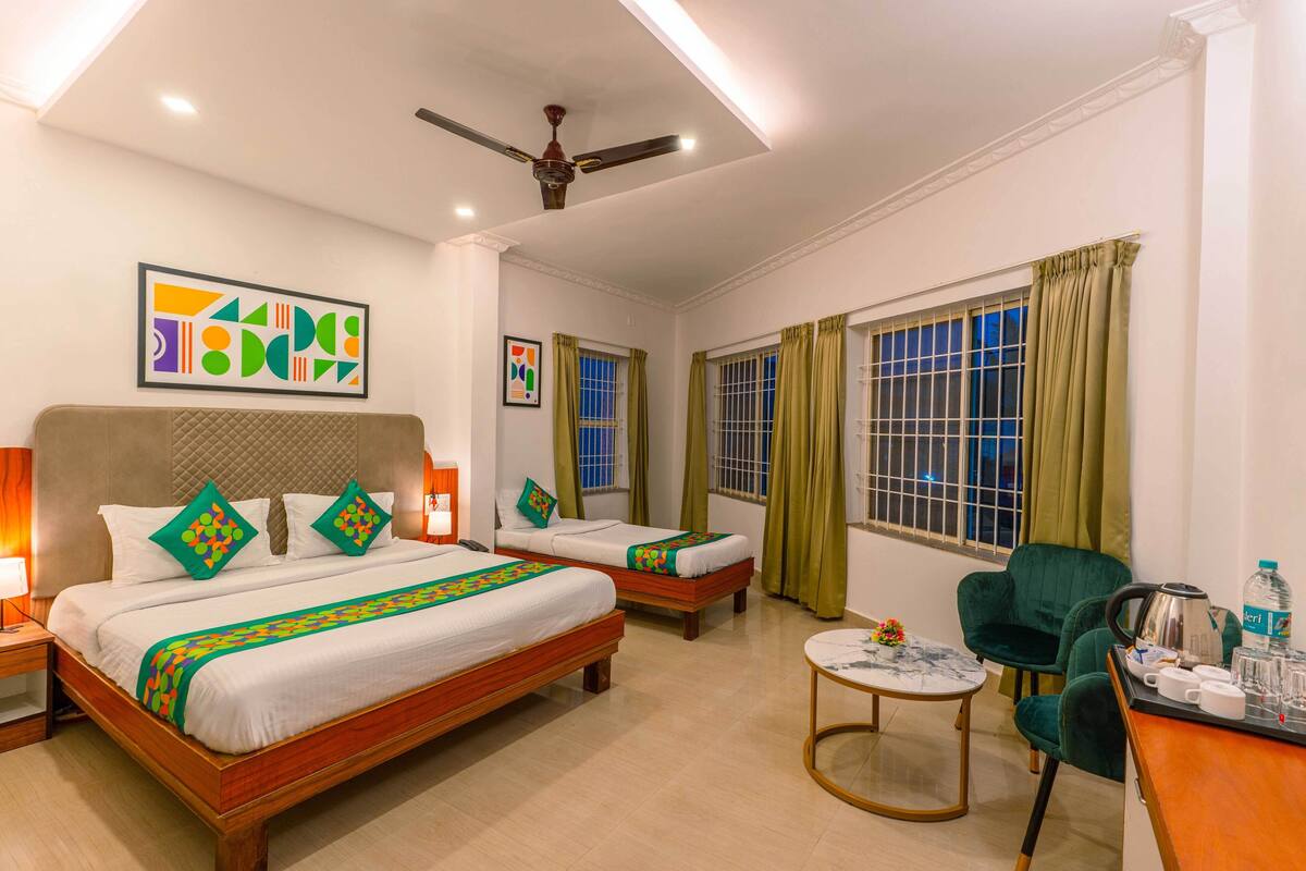 A hotel room with two beds, a desk, a chair, a ceiling fan, and artwork on the walls.