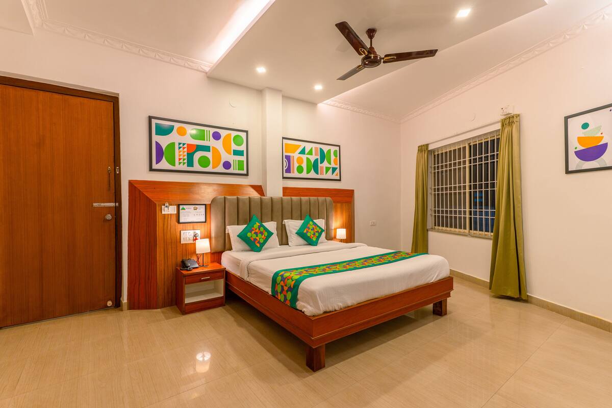 A hotel room with a wooden bed, a nightstand, a ceiling fan, and artwork on the walls.