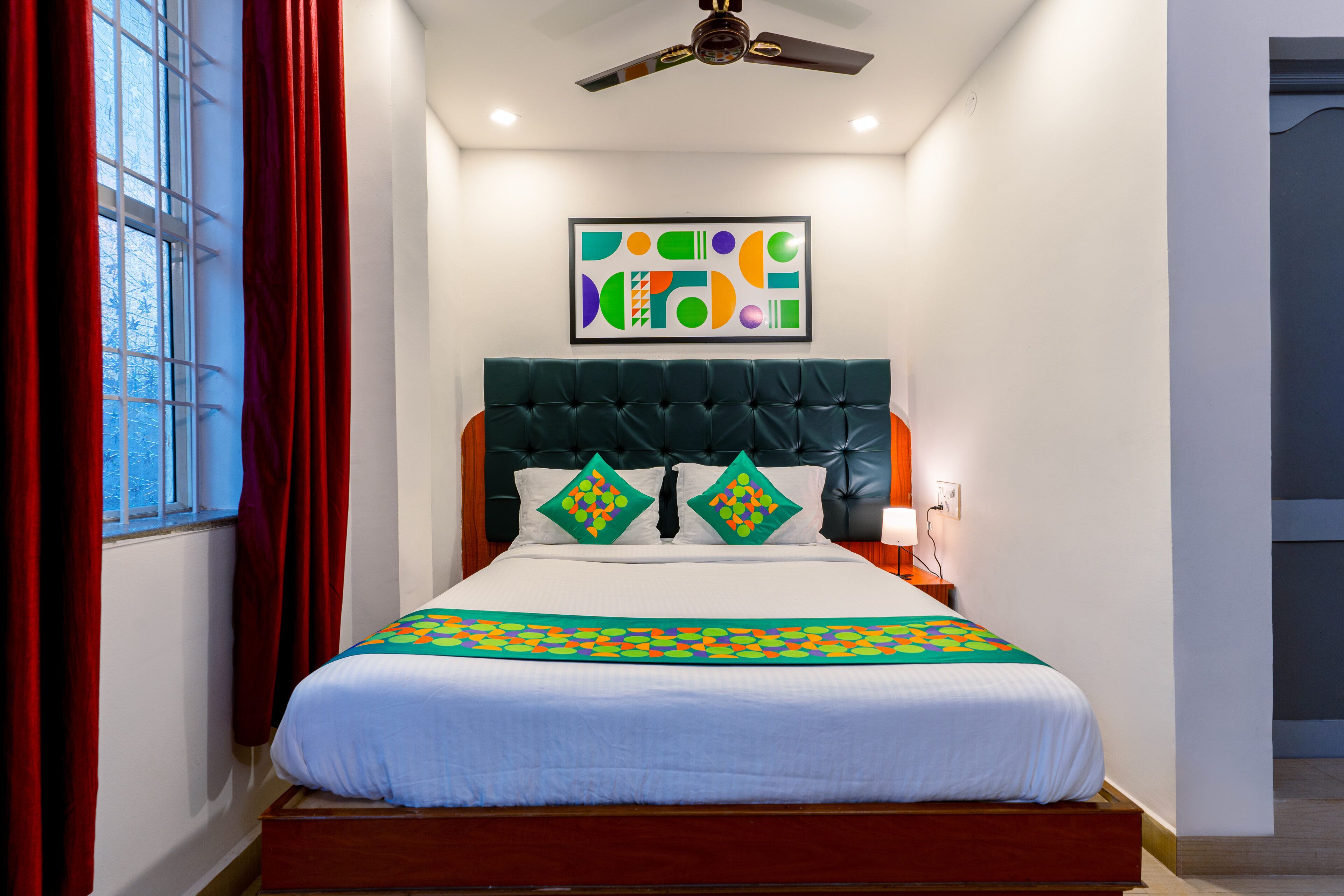 Una cama bien hecha con una colcha de estampado geométrico, cabecera capitonada y almohadones decorativos.