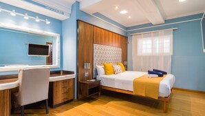 A hotel room with a bed, bedside table, and a desk with a chair.