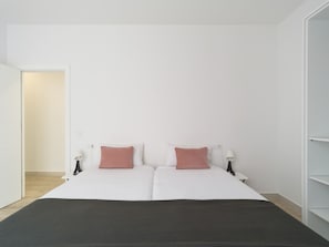 Un letto matrimoniale con due cuscini, un comodino con una lampada e un armadio.