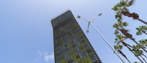 A tall, modern skyscraper with a unique, curved facade and a street lamp in the foreground.