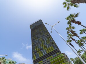 A tall, modern skyscraper with a unique, curved facade and a street lamp in the foreground.